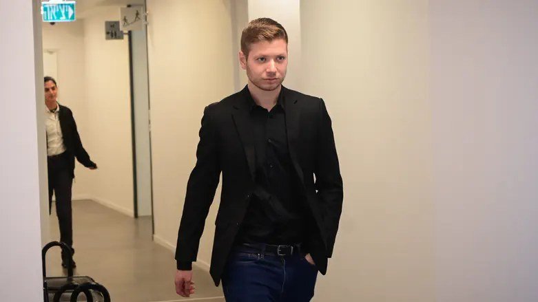 A man in a black suit walking down a hallway